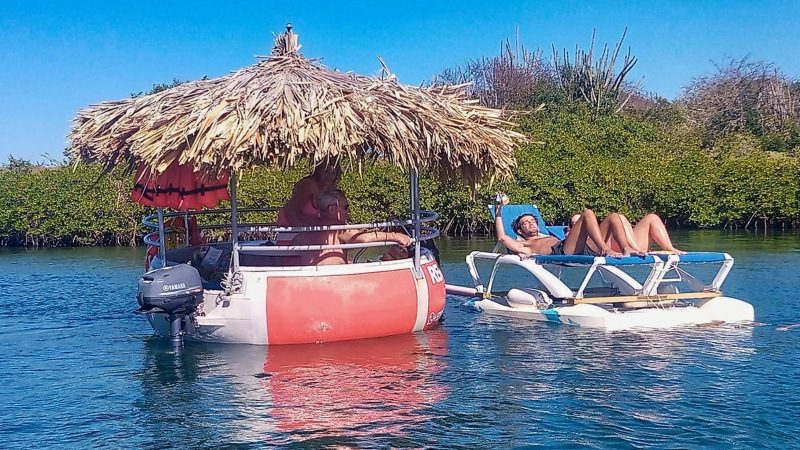Barco redondo Tiki Boats Curaçao com espreguiçadeira na água