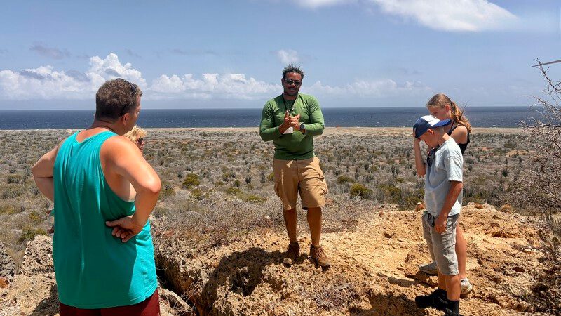 Met de jeep naar de oostkant van Curaçao: van botanische tuin tot off-road avontuur 9 Gids vertelt op het terras bij de grot tijdens de jeeptour oostkant Curaçao